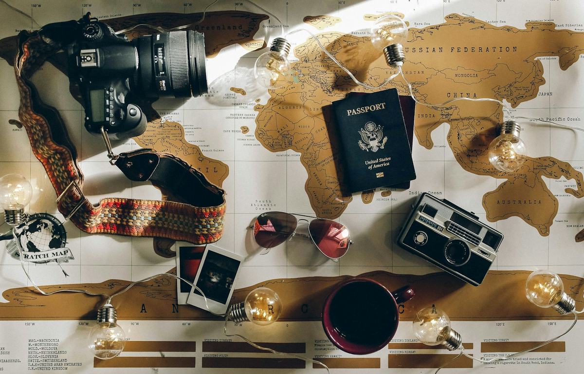 A world map with a passport, camera and travel essentials