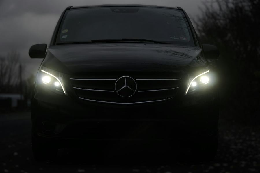 Front of a black Mercedes van with headlights on